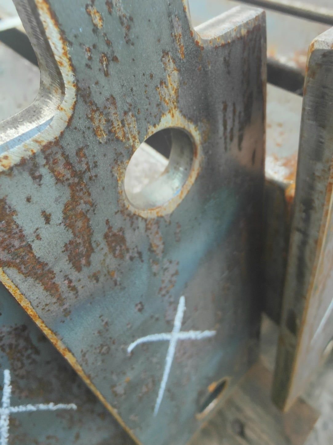 Rusty laser-cut steel plates marked up with chalk crosses before surface preparation