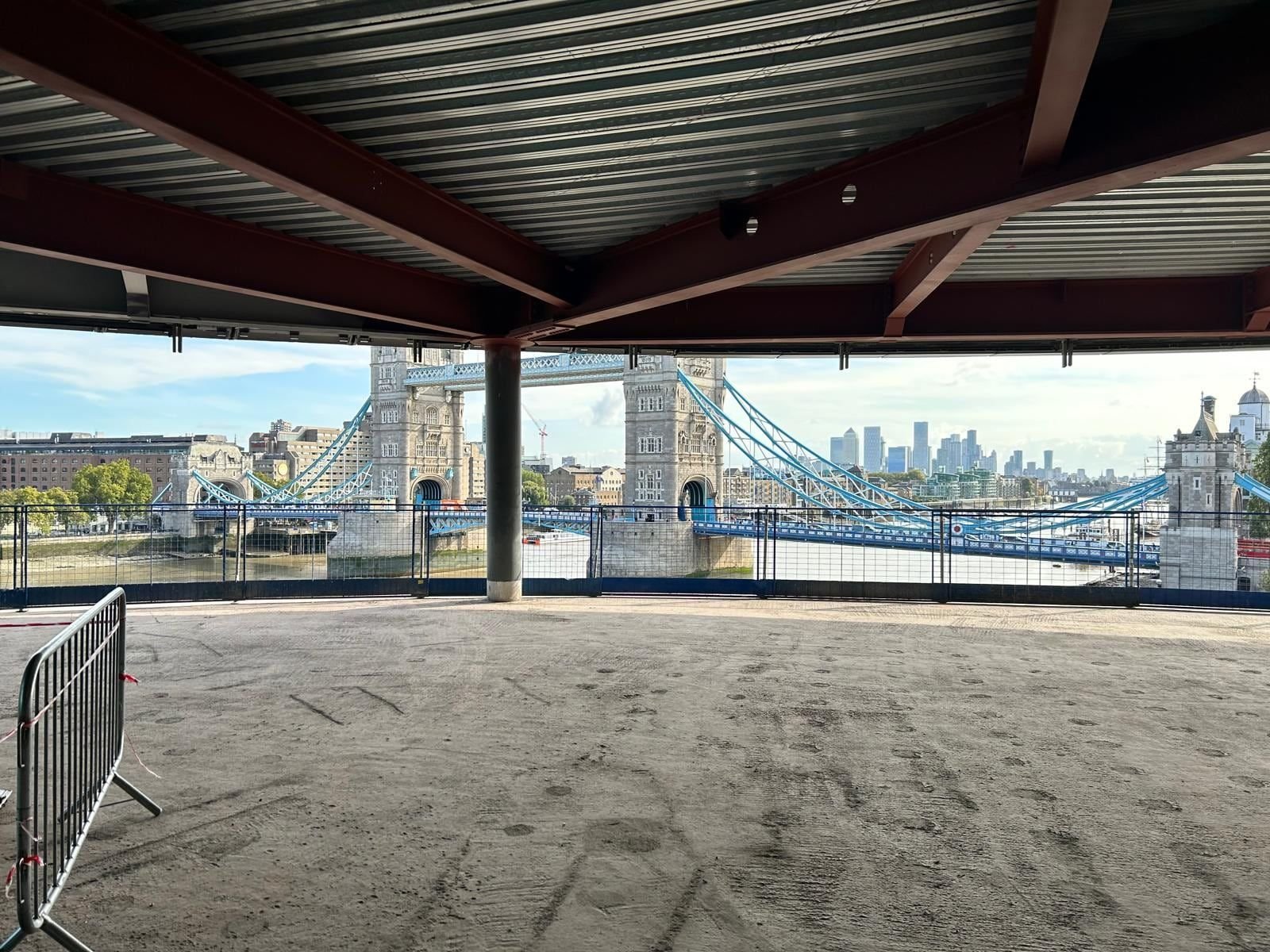 View of Tower Bridge from inside a steel-framed structure, with red-oxide painted beams overhead