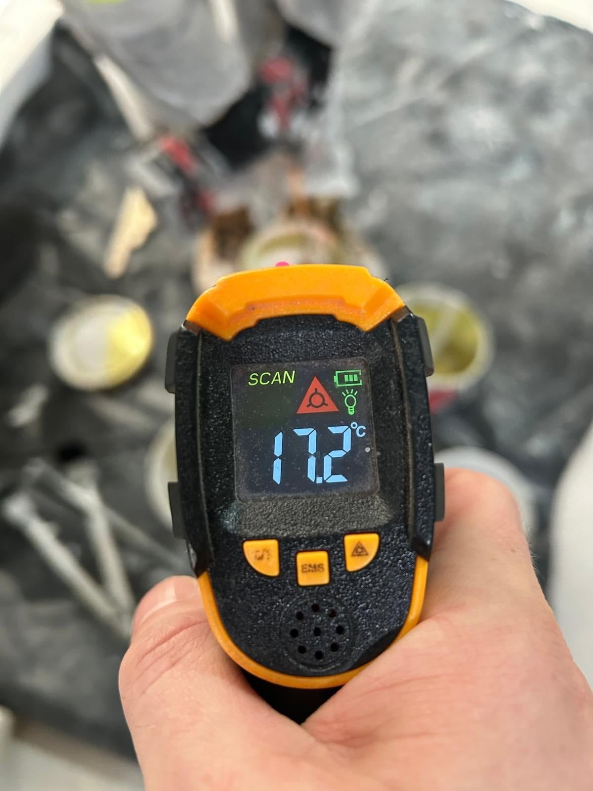 Infrared thermometer reading 17.2 degrees Celsius held over paint tins and a work area